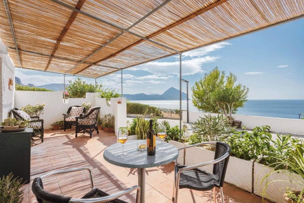 eine Terrasse mit einem Tisch, Stühlen und Meerblick in der Unterkunft Isulidda Gaia Mare in San Vito lo Capo