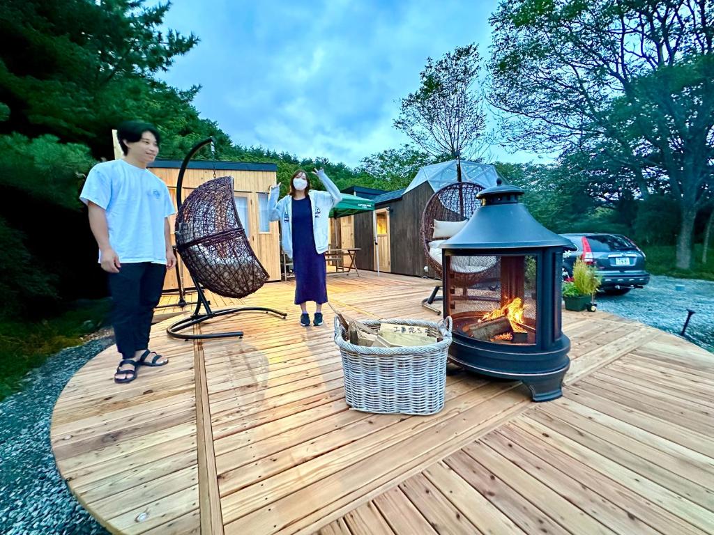 富士河口湖町にあるFuji Dome Glampingの木製のデッキ(火炉付)に立つ二人