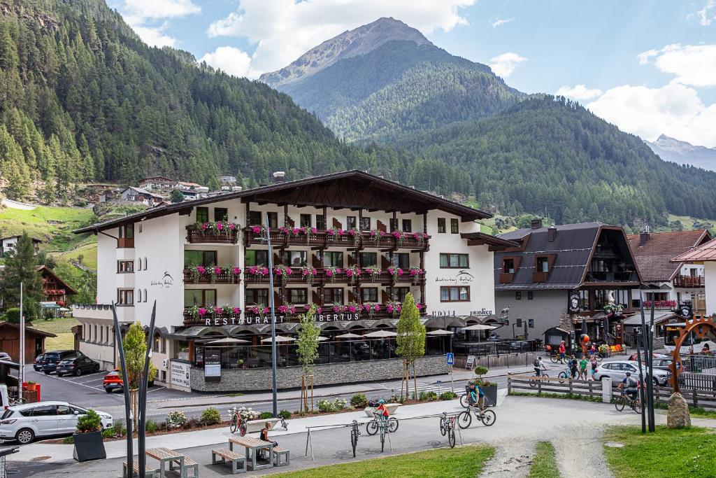 a large building in a town with mountains in the background at Hotel Hubertus inklusive Summercard in Sölden