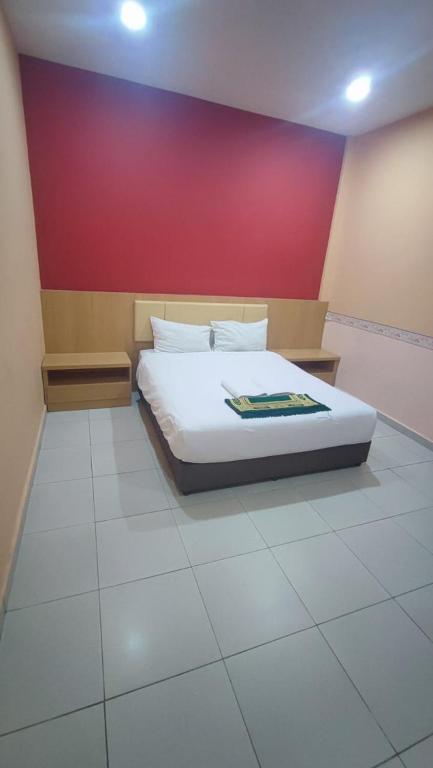 a bedroom with a white bed with a red wall at HOTEL PUTERI MIQAILA in Seri Iskandar