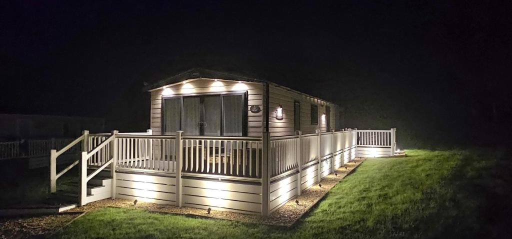 a cabin with lights on the side of it at night at Hot Tub Lodge Cornwall - Meadow Lakes Holiday Park in St Austell