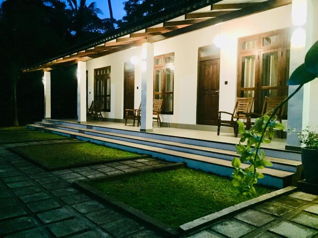 a house with a porch with chairs in front of it at Swan Lake Habarana in Habarana