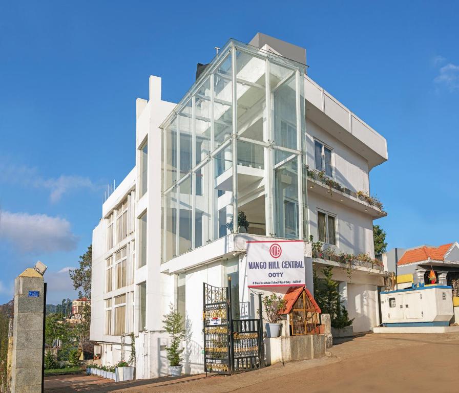 un bâtiment blanc avec un panneau devant lui dans l'établissement Mango Hill Central Ooty, à Ooty