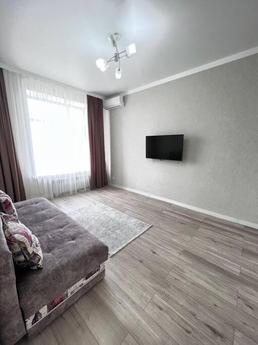 sala de estar con sofá y TV de pantalla plana en Прекрасное местечко Barys City, en Taldykolʼ