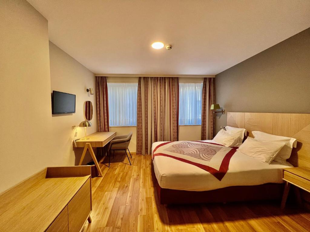 ブリュッセルにあるBedford Hotel & Congress Centre Brusselsのベッドとデスクが備わるホテルルームです。