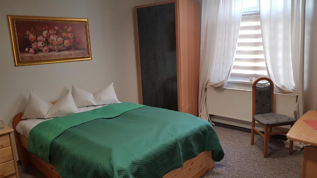 a bedroom with a green bed with a chair and a window at FEWO Begegnung mit Lounge in Bautzen