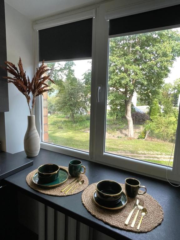 a table with three cups and saucers and a window at OzolApart in Jēkabpils
