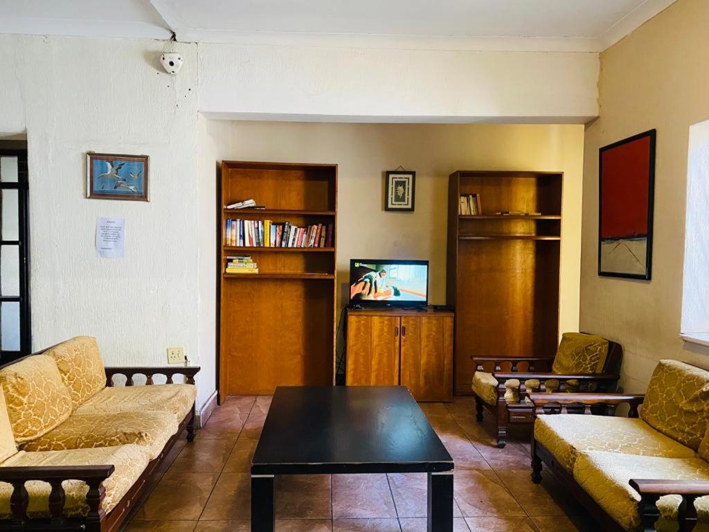 a living room with two couches and a tv at Rosebank Hostel in Johannesburg