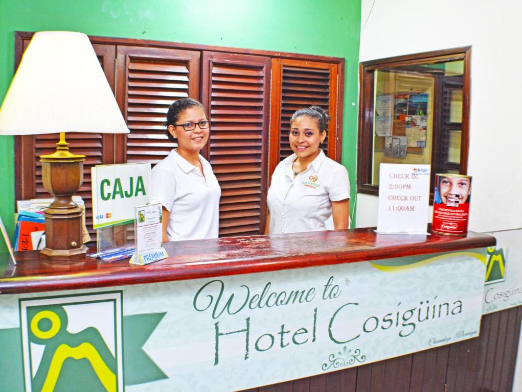 チナンデガにあるHotel Plaza Cosiguinaのホテルのフロントカウンターの後ろに立つ女性2名