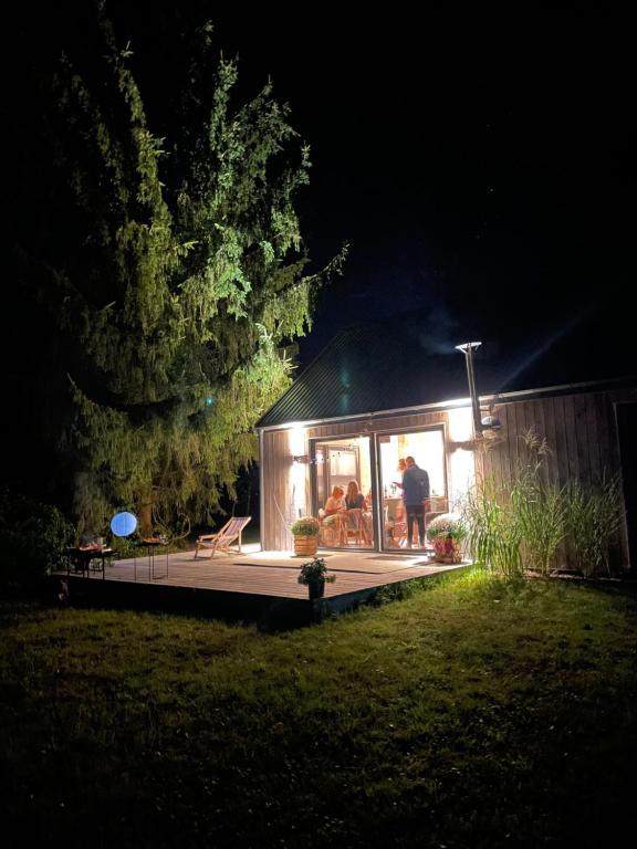 a man standing in front of a house at night at Domki Skandynawskie nad Pilicą, Duży Domek in Krzemień