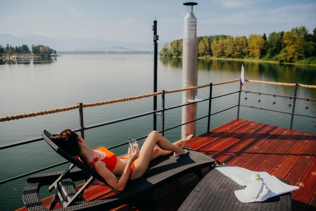 uma mulher deitada numa cadeira no convés de um barco em AQUACHILL houseboat & wellness em Liptovský Trnovec