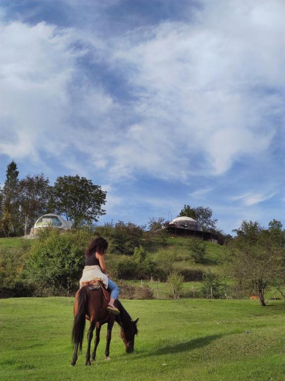 Una donna che cavalca un cavallo in un campo di Glamping Dream Domes Ismayilli a İsmayıllı