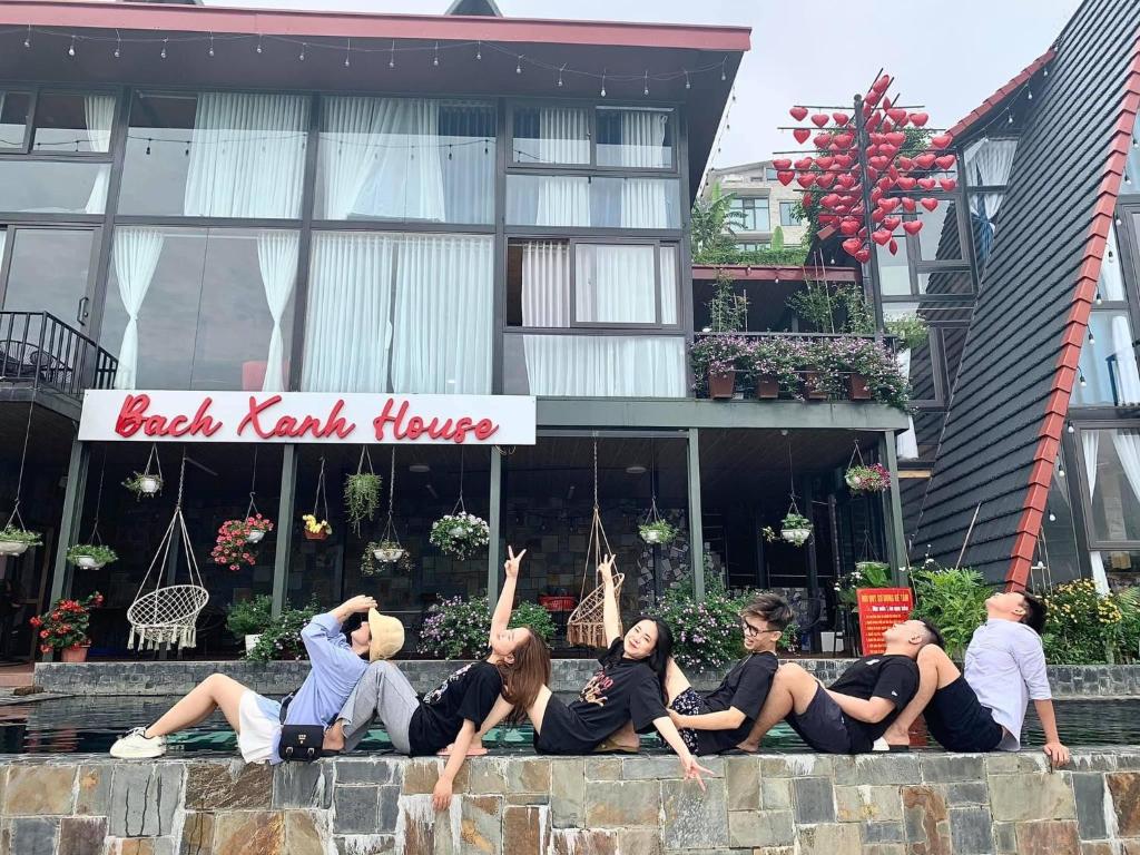 a group of people laying on a wall in front of a building at Bách Xanh House Venuestay in Vĩnh Phúc
