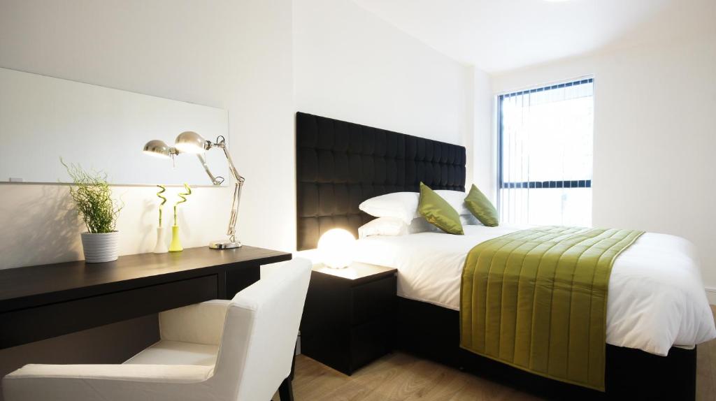 a bedroom with a bed and a desk with a chair at Andora Apartments in London