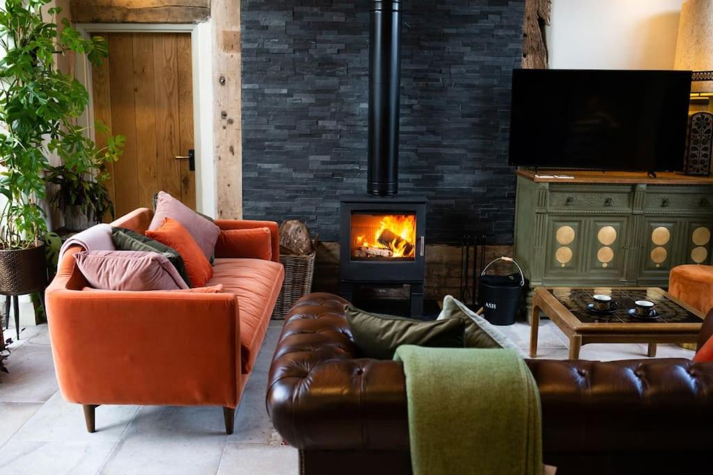 a living room with leather furniture and a fireplace at The Cart House - Beautiful Contemporary Barn - Hot Tub in Bridgnorth