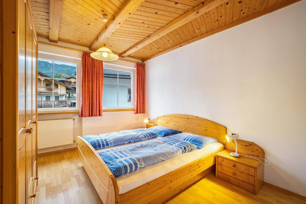 a bedroom with a wooden bed and a window at Kuenz Dolomites App Drau in San Candido