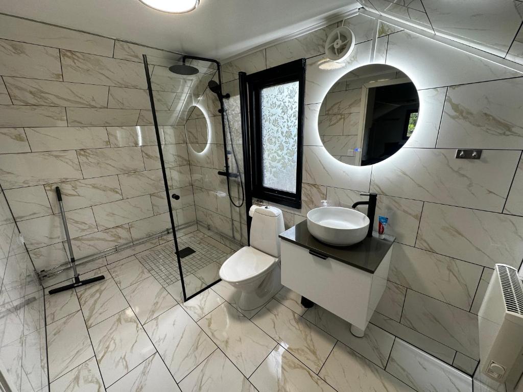 a bathroom with a toilet and a sink and a mirror at independent apartment near citycenter/lake in Borås