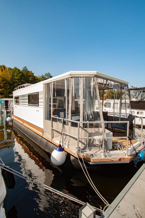 a white boat is docked at a dock at Hausboot in Hennigsdorf