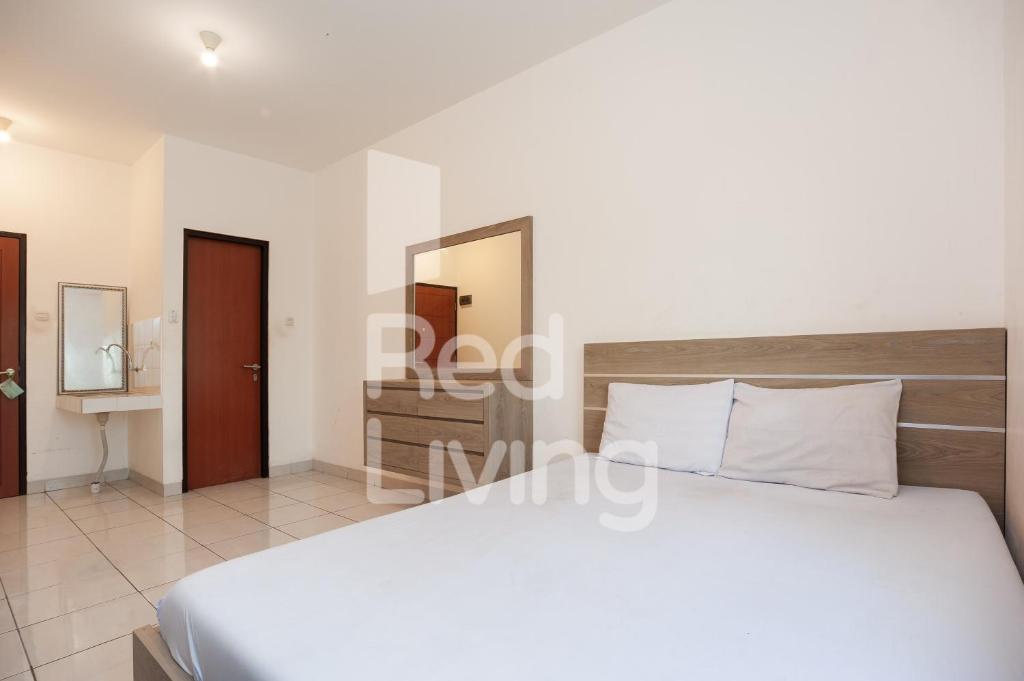 1 dormitorio con cama blanca y espejo en RedLiving Apartemen EcoHome - DeLouvre Tower A Suginoki, en Nalagat