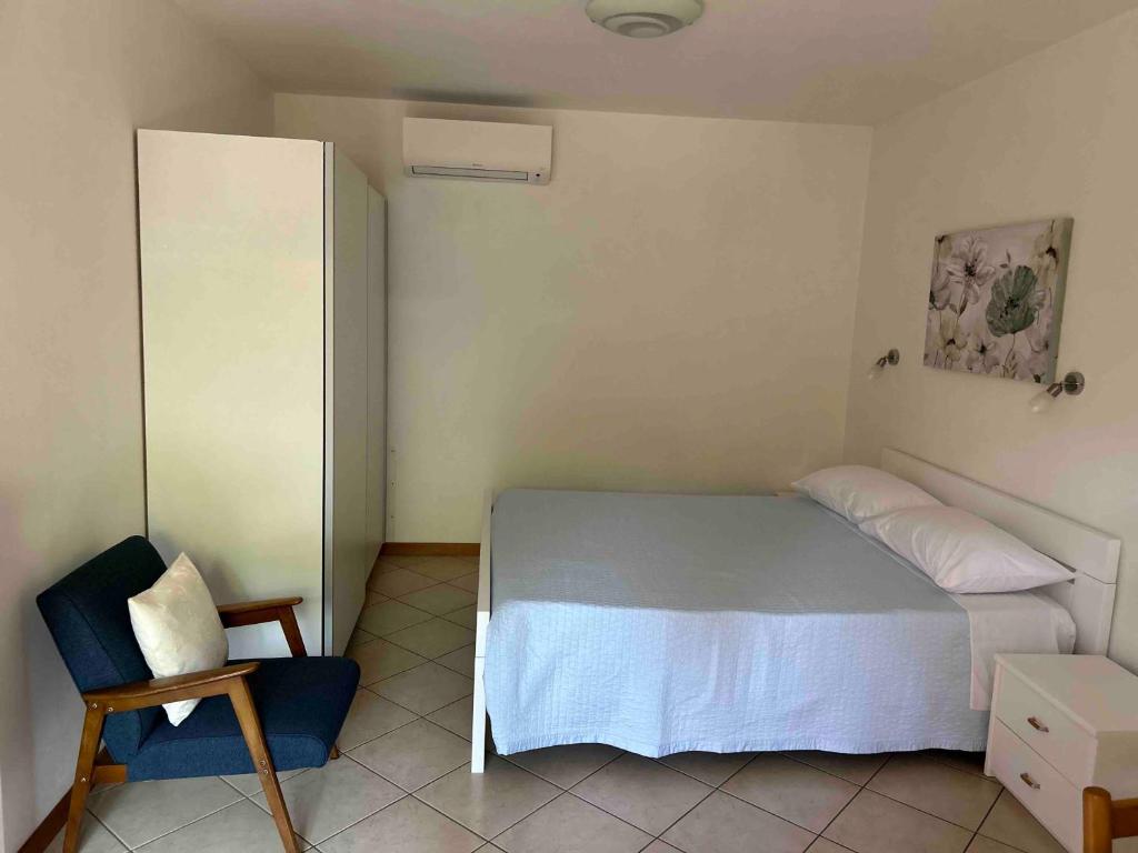 una piccola camera con letto e sedia di Ai 2 Olmi - monolocali nel verde a Múggia