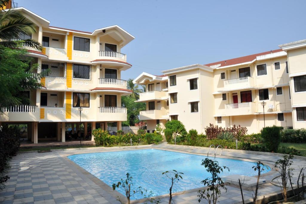 an apartment complex with a swimming pool in front of a building at Cozy Haven Luxury Holiday Home in Majorda