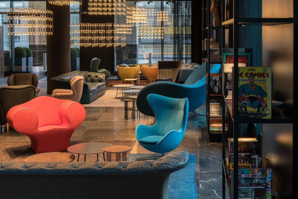 um átrio com cadeiras e mesas coloridas em Motel One Berlin-Alexanderplatz em Berlim