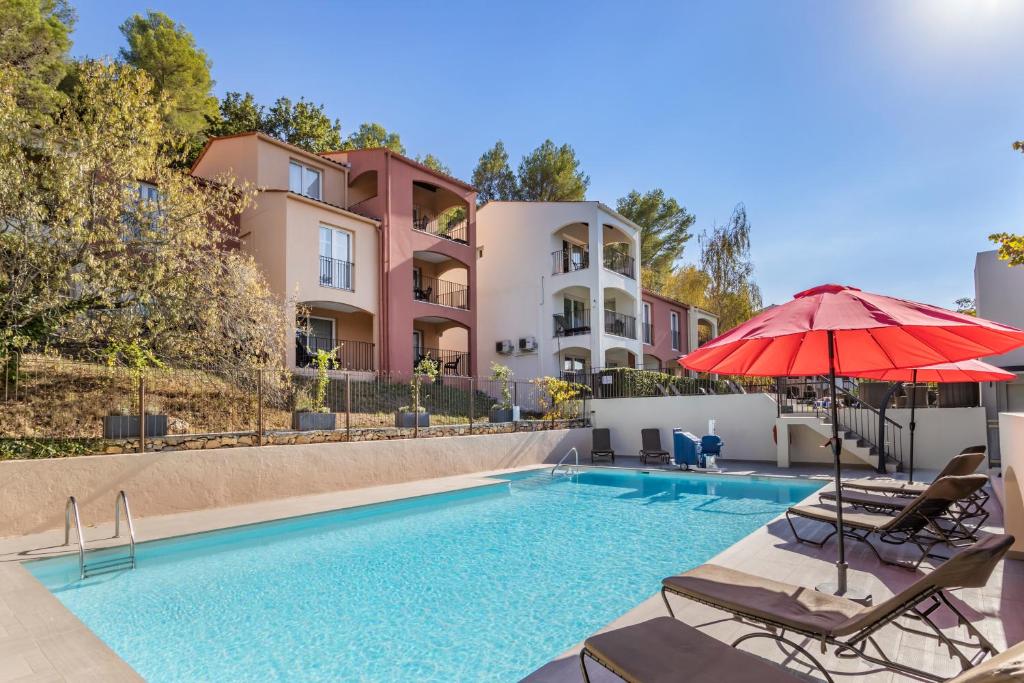 een zwembad met stoelen en een parasol naast een gebouw bij Le Club Mougins in Mougins