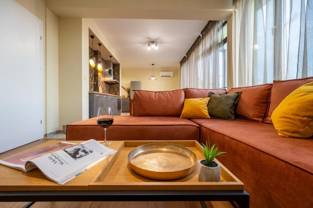 a living room with a brown couch and a table at Three Lilies Apartments in Plovdiv