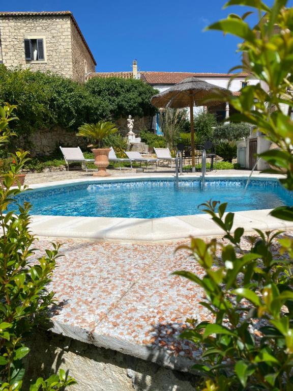 einen Pool mit Stühlen und einem Sonnenschirm in der Unterkunft Sa domu de don Ninnu bed breakfast Spa in Gesturi