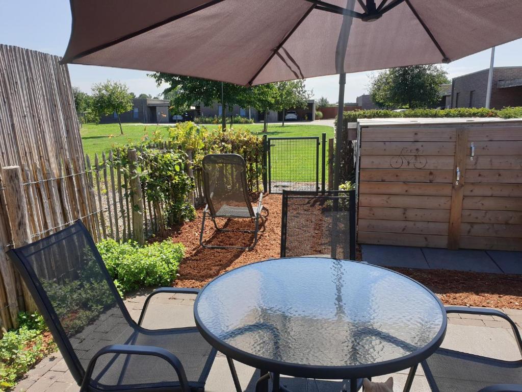 - une table et des chaises avec un parasol sur la terrasse dans l'établissement Het Zonnetje -Vakantiewoning en Bed and Breakfast, à Dilsen-Stokkem