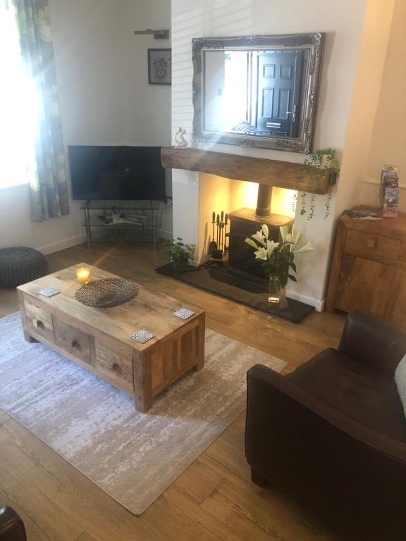 uma sala de estar com uma mesa de centro e uma televisão em Riverside Cottage em Whalley