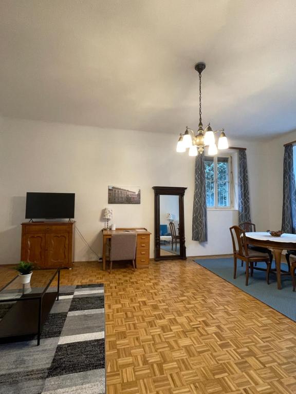 an empty living room with a table and a television at Altbauwohnung im Herzen vom Lend in Graz