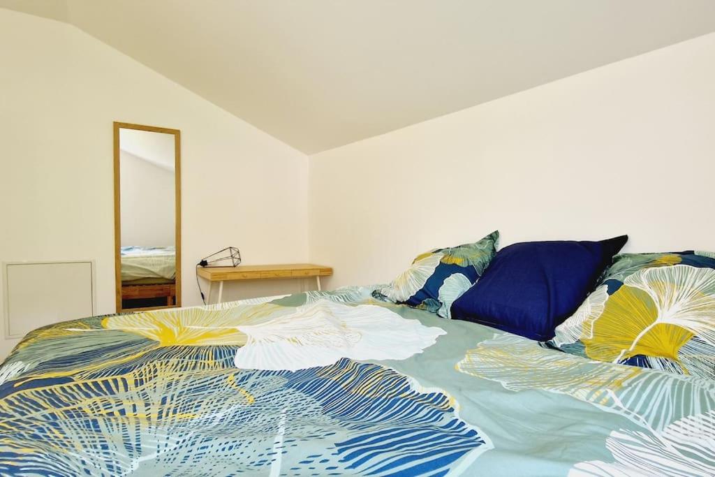 a bed with a colorful comforter and pillows on it at Le Rocher YourHostHelper in Fontanil-Cornillon