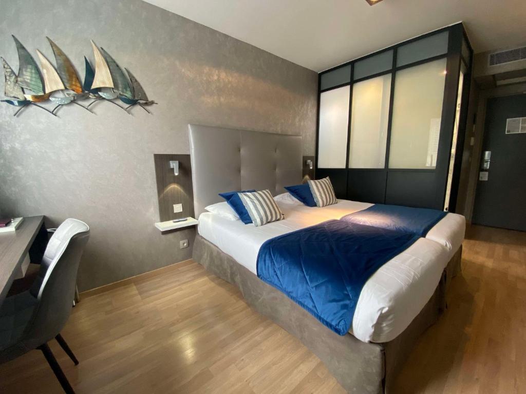 a bedroom with a large bed with blue sheets at Hotel Best Western La Mare Ô Poissons in Ouistreham