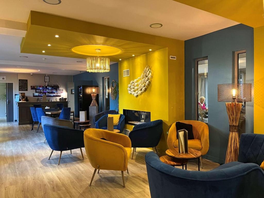 a lobby with blue chairs and a yellow wall at Hotel Best Western La Mare Ô Poissons in Ouistreham