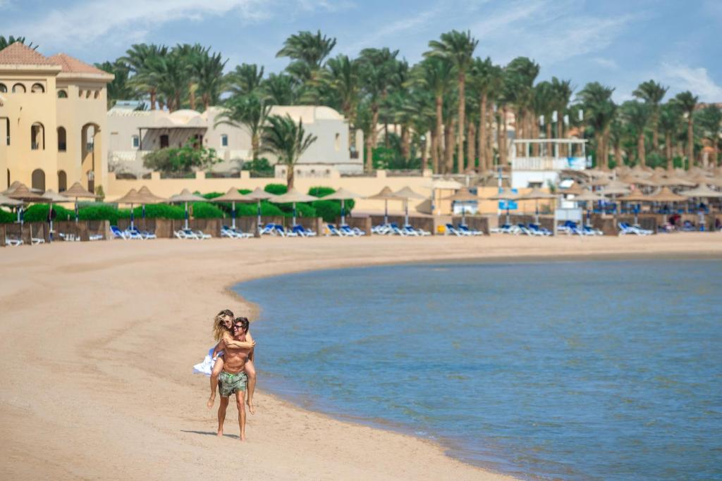 Cleopatra Luxury Resort Makadi Bay في الغردقة: امرأة وطفل على الشاطئ