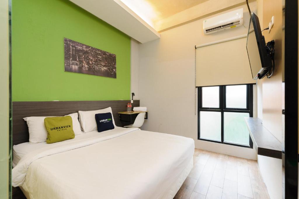 a bedroom with a white bed and a green wall at Sans Stay Caverna Gandaria in Jakarta