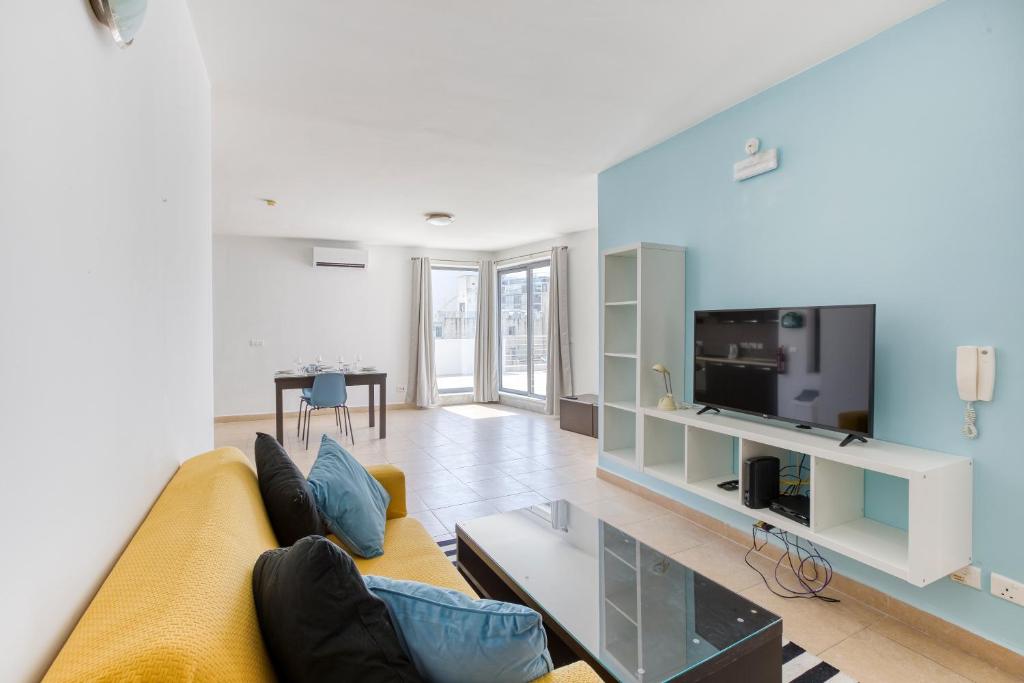 a living room with a yellow couch and a tv at 1BR penthouse with Large Private Terrace in PV by 360 Estates in St. Julianʼs