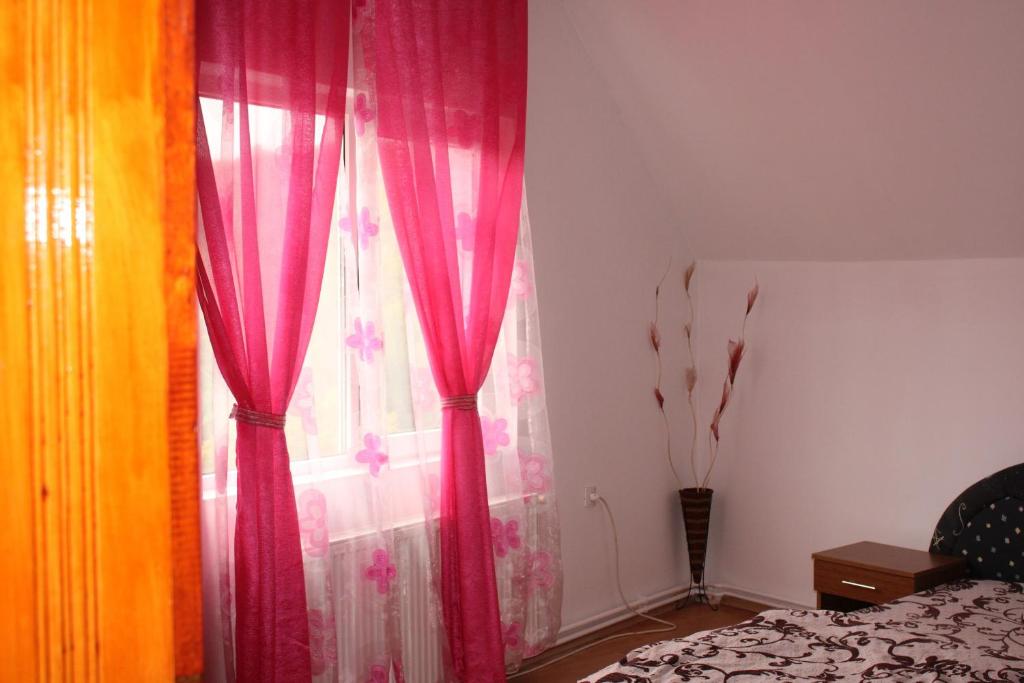 a bedroom with pink curtains and a window at Casa Dănuț in Reşiţa