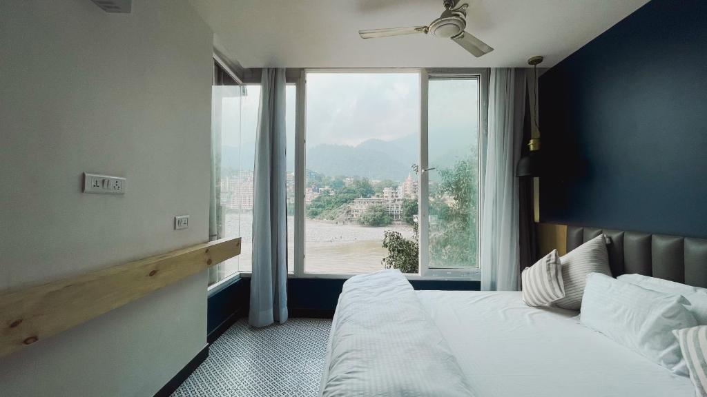 a bedroom with a bed and a large window at Joey's By The Ganges in Rishīkesh