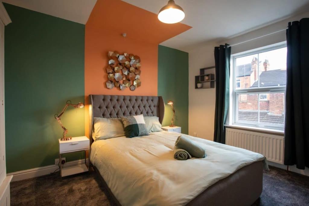 a bedroom with a bed with an orange and green wall at Cosy home in City Centre in Lincolnshire