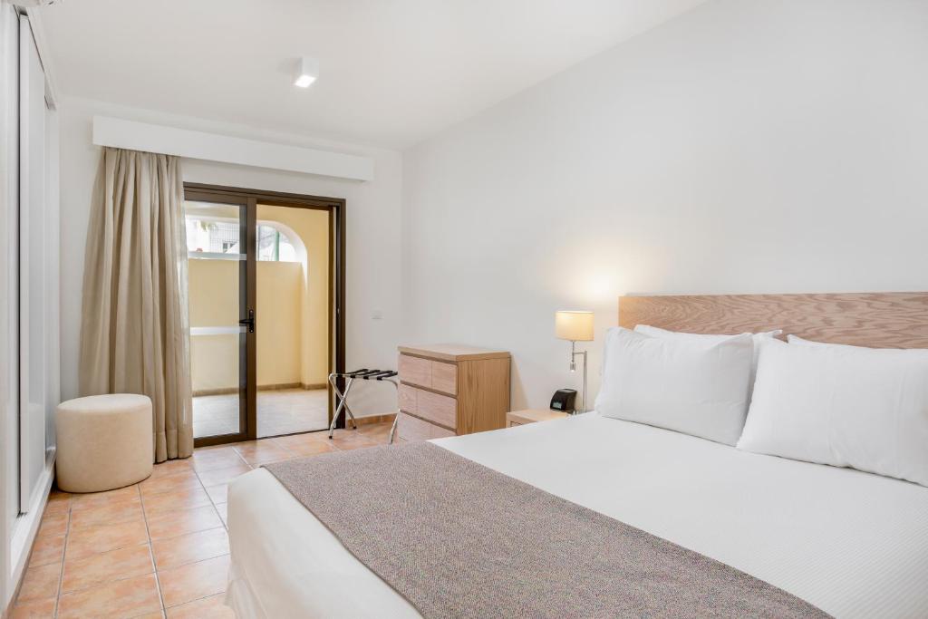 a bedroom with a large white bed and a desk at Royal Sunset Beach Club in Adeje