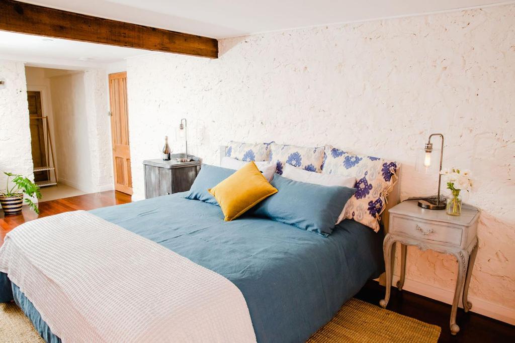 a bedroom with a bed with blue and yellow pillows at Orange Door Bnb in Currency Creek