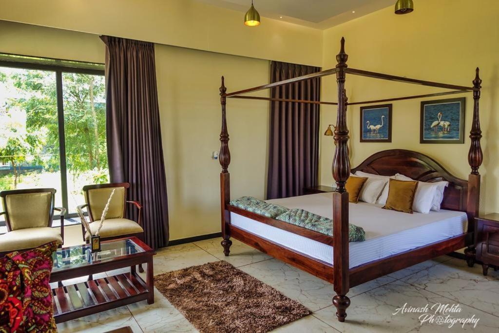 um quarto com uma cama de dossel e uma cadeira em Jawai Greens em Jawāi Bāndh