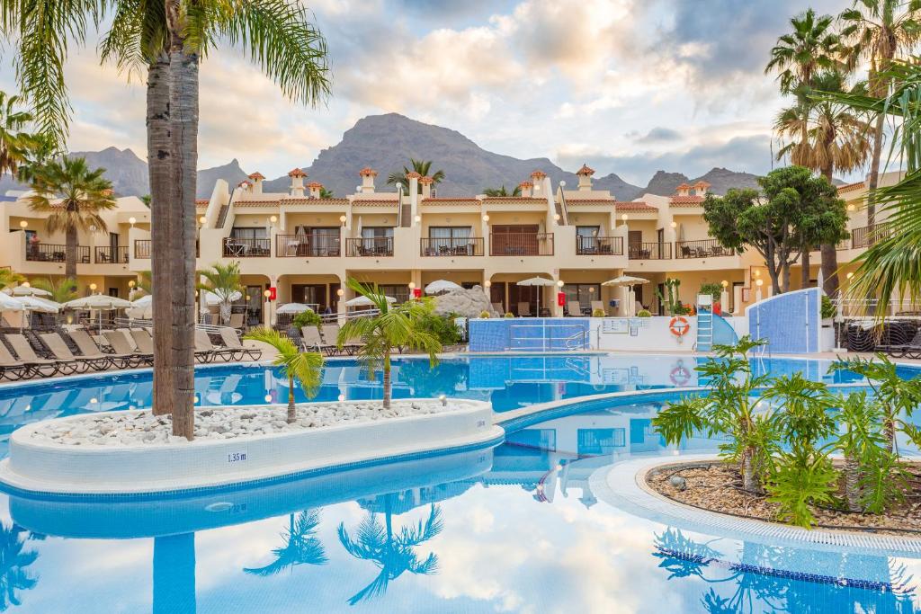 a resort with a pool with palm trees and a building at Royal Sunset Beach Club in Adeje