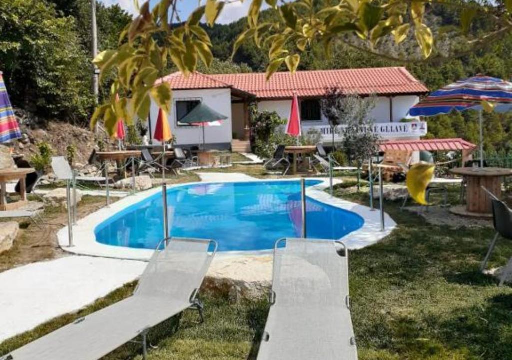 una piscina en un patio con sillas y sombrillas en Vila Sofia Gllava - Resort en Memaliaj