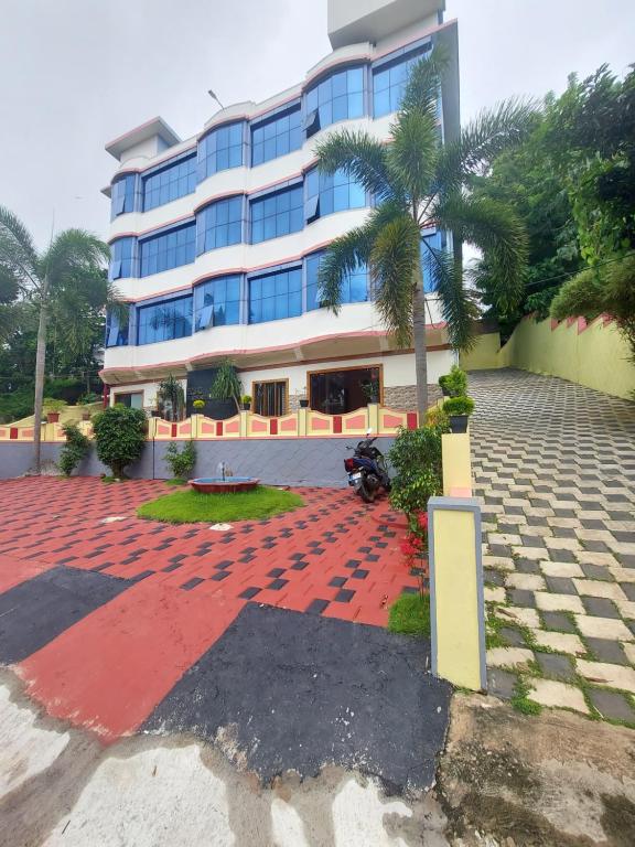 um edifício com uma palmeira em frente em Padmatheertham Inn em Varkala
