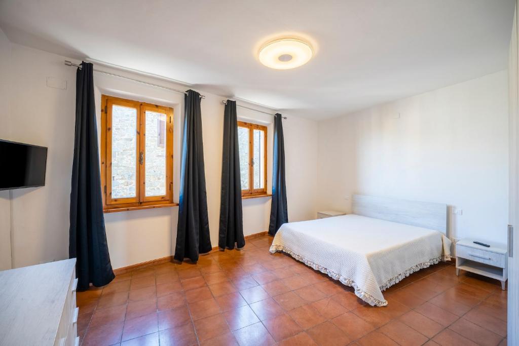 - une chambre avec un lit, une télévision et des fenêtres dans l'établissement BORGO SMOL, à Chianni