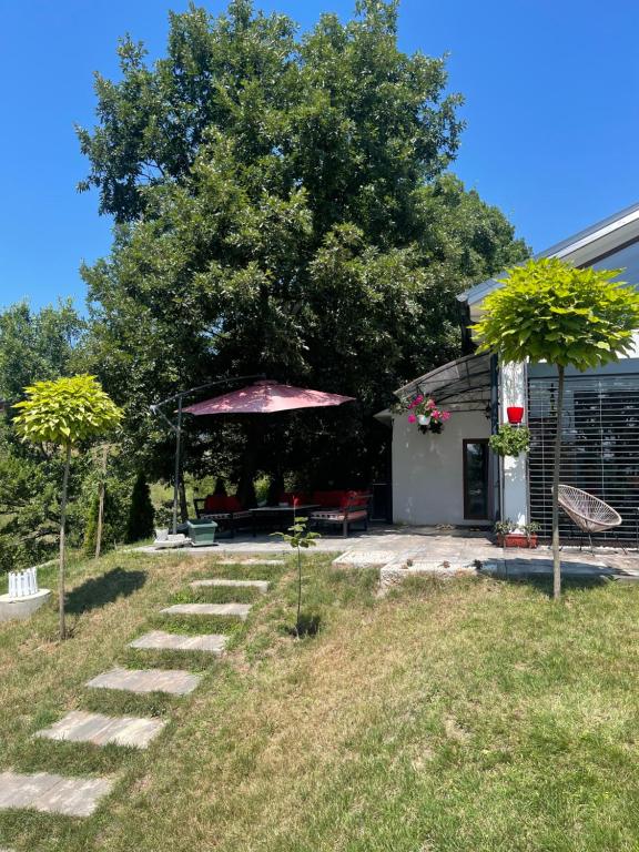 einen Garten mit einer Bank und einem Sonnenschirm in der Unterkunft Villa fg in Gnjilane