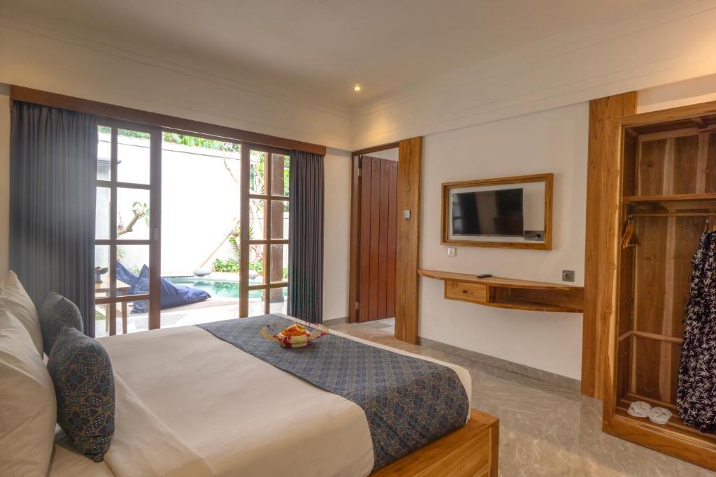 een slaapkamer met een bed en een tv in een kamer bij De Rekun Ubud in Ubud